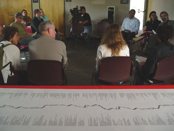 visual text piece on table with seminar happening  in room behind